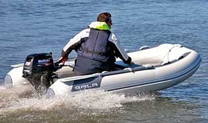 Man boating along the shore in a Gala aluminum rigid inflatable boat (RIB) equipped with seating and Suzuki outboard motor.