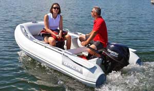 Couple riding around the marina in a Gala 11ft foldable inflatable boat dinghy rigged with a 9.8HP Tohatsu outboard motor.