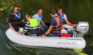 Crew boating to the lake's shore in a Gala foldable inflatable boat dinghy equipped with a Honda outboard motor.